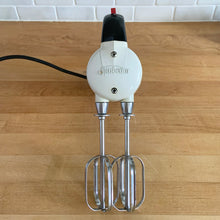 Load image into Gallery viewer, Fabulous vintage white and black Sunbeam Mixmaster Junior hand mixer, Model J. Crafted by the Sunbeam Corporation, USA, circa 1950. The power and quality craftsmanship of these mixers is unmatched and are made to last a lifetime. A must-have for any baker or appliance collector!
Tested. In good working order.
Mixer measures 7 1/4 x 3 x 6 inches (10 3/4 inches tall with beaters)
