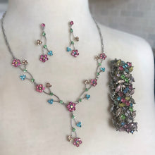 Load image into Gallery viewer, Floral necklace with matching stud drop pierced style earrings and stretch bracelet featuring rhinestone crystals in pink, aurora borealis, light blue, peridot green and yellow. Silver-toned imitation platium plated findings and the earring posts are made with sterling silver.
In excellent condition.