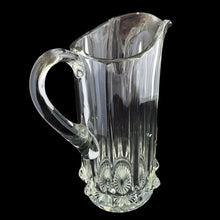 Load image into Gallery viewer, Antique National Glass Co. Hercules clear glass pitcher, angled three-quarter view from handle side showing ribbed body, applied handle, and pressed star base, c. 1904