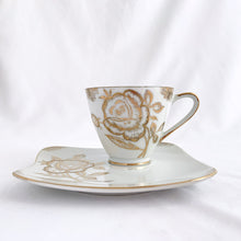 Load image into Gallery viewer, This vintage white porcelain teacup and saucer is absolutely stunning! The unique polygon shaped saucer and teacup are decorated with hand painted gold gilt roses and details. Produced in Japan. In good vintage condition, free from chips, cracks and repairs. Marked "Oakwood Hand Painted Japan". Teacup measures 3 3/14 x 2 3/4 inches | Saucer measures 5 3/4 x 5 x 5 3/4 inches