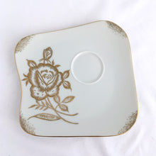 Load image into Gallery viewer, This vintage white porcelain teacup and saucer is absolutely stunning! The unique polygon shaped saucer and teacup are decorated with hand painted gold gilt roses and details. Produced in Japan. In good vintage condition, free from chips, cracks and repairs. Marked "Oakwood Hand Painted Japan". Teacup measures 3 3/14 x 2 3/4 inches | Saucer measures 5 3/4 x 5 x 5 3/4 inches