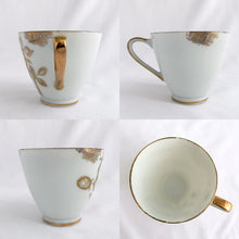 Load image into Gallery viewer, This vintage white porcelain teacup and saucer is absolutely stunning! The unique polygon shaped saucer and teacup are decorated with hand painted gold gilt roses and details. Produced in Japan. In good vintage condition, free from chips, cracks and repairs. Marked "Oakwood Hand Painted Japan". Teacup measures 3 3/14 x 2 3/4 inches | Saucer measures 5 3/4 x 5 x 5 3/4 inches