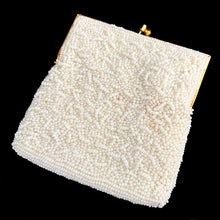 Load image into Gallery viewer, Stunning handmade vintage mid-century era evening bag adorned in creamy off-white glass seed beads, topped with gold-toned hardware, snake chain handle and kiss closure. The interior is lined with cream satin and has an open pocket. The bag is large enough for a small cell phone, credit cards/cash, compact/lipstick. Beautifully styled by Artel Montreal and made in Hong Kong, 1950s. An absolutely stunning piece that would make an incredible bridal or formal occasion accessory!