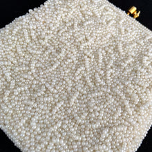 Load image into Gallery viewer, Stunning handmade vintage mid-century era evening bag adorned in creamy off-white glass seed beads, topped with gold-toned hardware, snake chain handle and kiss closure. The interior is lined with cream satin and has an open pocket. The bag is large enough for a small cell phone, credit cards/cash, compact/lipstick. Beautifully styled by Artel Montreal and made in Hong Kong, 1950s. An absolutely stunning piece that would make an incredible bridal or formal occasion accessory!