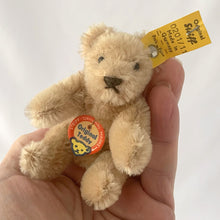 Load image into Gallery viewer, Vintage Original Teddy miniature beige bear made beige mohair. He has a brown hand embroidered nose and mouth, black beaded eyes and his head is jointed and bendable limbs. Silver button-in-ear with yellow tag. His chest has the red, blue and yellow white tag. Steiff, Germany, 1969 - 1977. A must-have for any Steiff or teddy bear collector! In excellent condition. Purchased from the original owner who kept it in a display case. Measures 2 3/4 inches or 7cm tall