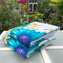 Load image into Gallery viewer, A vintage pale blue ultra soft cotton terry cloth bath towels featuring a striking spray of flowers in shades of turquoise, blue and green with an inset scalloped border pattern. Crafted by Besana, Italy. This gorgeous towel is sure to amplify your bath! In excellent condition, free form tears/stains. Possibly new old stock. Measures 47 inches x 27 1/2 inches