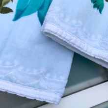 Load image into Gallery viewer, A vintage pale blue ultra soft cotton terry cloth bath towels featuring a striking spray of flowers in shades of turquoise, blue and green with an inset scalloped border pattern. Crafted by Besana, Italy. This gorgeous towel is sure to amplify your bath! In excellent condition, free form tears/stains. Possibly new old stock. Measures 47 inches x 27 1/2 inches