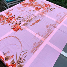Load image into Gallery viewer, We are suckers for gorgeous linens and this piece does not disappoint! This strikingly unique vintage Barbie pink linen tablecloth features a printed pattern of roses and Chinoiserie river scenes and pagodas in shades of orange, brown and ochre . A conversation piece for your table!~ This piece is new old stock and does not appear to have been used to laundered and is in excellent condition. Measures 52 x 85 inches