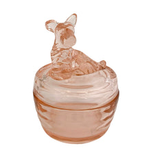 Load image into Gallery viewer, Vintage Jeannette Glass pink depression glass powder jar with lid, three-quarter front view, rounded ribbed base in blush pink glass, flat domed lid topped with a moulded seated terrier dog finial facing left with pointed ears and textured fur detail
