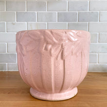 Load image into Gallery viewer, Rare vintage matte pink Sand Butterfly jardiniere planter with embossed vertical bands topped with a border of leaves and butterflies. Crafted by McCoy Pottery, 1930s. This rare planter is must for any McCoy art pottery collector. A wonderful piece to elevate your home and garden decor or to give as a gift!
In as found vintage condition, chips to the rim and crack, no repairs. Normal age-related crazing and manufacturer's glaze pops. Maker's mark on the bottom.
Measures 8 x 7 inches