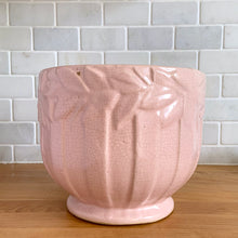 Load image into Gallery viewer, Rare vintage matte pink Sand Butterfly jardiniere planter with embossed vertical bands topped with a border of leaves and butterflies. Crafted by McCoy Pottery, 1930s. This rare planter is must for any McCoy art pottery collector. A wonderful piece to elevate your home and garden decor or to give as a gift!
In as found vintage condition, chips to the rim and crack, no repairs. Normal age-related crazing and manufacturer's glaze pops. Maker's mark on the bottom.
Measures 8 x 7 inches