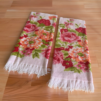 Vintage 100% cotton oversized pink terry cloth hand towel featuring flowers in shades of pink and orange, with green flowers and fringed edges. Crafted by Cannon, USA, circa 1970s. In good used condition, free from stains/tears. Measures 21 1/2 x 42 inches