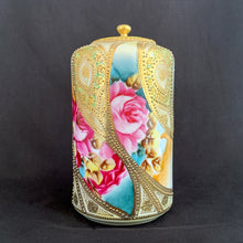 Load image into Gallery viewer, Absolutely exquisite vintage hand painted porcelain lidded ginger jar, crafted by artisans in Japan, late 1800s - early 1900s. It features sweeping panes of pink roses against a yellow and deep teal with alternating peacock feather-like shapes of gold gilt, heavily embellished with moriage, as is the lid. According to Kovels, Nippon Porcelain dates between 1891-1921. After that, US law required imports to be labeled with the country of origin in English. This one-of-a-kind piece.