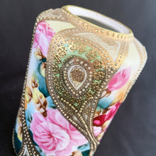 Load image into Gallery viewer, Absolutely exquisite vintage hand painted porcelain lidded ginger jar, crafted by artisans in Japan, late 1800s - early 1900s. It features sweeping panes of pink roses against a yellow and deep teal with alternating peacock feather-like shapes of gold gilt, heavily embellished with moriage, as is the lid. According to Kovels, Nippon Porcelain dates between 1891-1921. After that, US law required imports to be labeled with the country of origin in English. This one-of-a-kind piece.