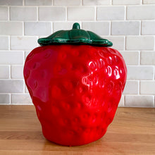 Load image into Gallery viewer, Rare vintage retro figural red strawberry cookie jar, topped with green lid. Crafted by McCoy Pottery, USA, 1970s. A good sized stoneware canister for a large batch of cookies that will look great as part of your kitchen decor!
In vintage condition, no chips/cracks/repairs, scuffing at the rim of the strawberry. Maker's mark on bottom.
Measures 7 1/4 x 9 3/4 inches