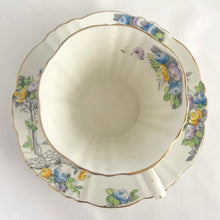 Load image into Gallery viewer, Vintage art deco white bone china teacup and saucer is absolutely gorgeous! Produced by Royal Albert, England, circa 1927 - 1935. Decorated in the "Rosalie" pattern which depicts a hand painted garden path featuring a trellis filled with blue, purple and yellow flowers, trimmed with gold gilt. Excellent condition, free from chips, cracks and repairs. Maker's marks are on the bottom. Teacup measures 3 3/8 x 2 3/4 inches | Saucer measures 5 1/4 inches