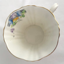 Load image into Gallery viewer, Vintage art deco white bone china teacup and saucer is absolutely gorgeous! Produced by Royal Albert, England, circa 1927 - 1935. Decorated in the "Rosalie" pattern which depicts a hand painted garden path featuring a trellis filled with blue, purple and yellow flowers, trimmed with gold gilt. Excellent condition, free from chips, cracks and repairs. Maker's marks are on the bottom. Teacup measures 3 3/8 x 2 3/4 inches | Saucer measures 5 1/4 inches