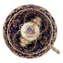 Load image into Gallery viewer, Vintage Royalty Bone China teacup and saucer features a hand painted cobalt blue interior on a white ground, lavishly decorated with gold gilt flowers and fluorishes, complemented by colourful florals in the bottom of the cup and centre of the saucer. Aynsley, England. 1934 - 1950s. In excellent condition, no chips/cracks/repairs. Teacup measures 4 x 2 1/4 Saucer measures 5 3/4