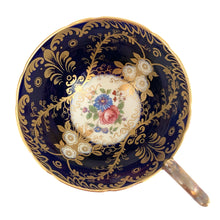 Load image into Gallery viewer, Vintage Royalty Bone China teacup and saucer features a hand painted cobalt blue interior on a white ground, lavishly decorated with gold gilt flowers and fluorishes, complemented by colourful florals in the bottom of the cup and centre of the saucer. Aynsley, England. 1934 - 1950s. In excellent condition, no chips/cracks/repairs. Teacup measures 4 x 2 1/4 Saucer measures 5 3/4