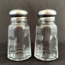 Load image into Gallery viewer, Vintage clear pressed glass paneled salt and pepper shakers with stainless steel lids. Crafted by Dominion Glass, Canada, 1950s. Classic tableware that's always in style!
The glass is in excellent condition, no chips, minor wear to the lids.
Measures 1 3/8 x 3 inches