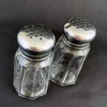 Load image into Gallery viewer, Vintage clear pressed glass paneled salt and pepper shakers with stainless steel lids. Crafted by Dominion Glass, Canada, 1950s. Classic tableware that's always in style!
The glass is in excellent condition, no chips, minor wear to the lids.
Measures 1 3/8 x 3 inches