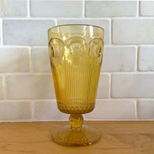 Load image into Gallery viewer, Known as the "crystal of the southwest", this "St. Genevieve" amber pressed glass footed iced tea goblet is striking with its beautifully designed series of arches, dots and cut vertical ribs, ball stem and round star foot. Produced by the Bartlett-Collins Glass Company, USA, between 1950-1970. A great piece to add to your drinkware collection! In excellent condition, free from chips/cracks. Measures approximately 3 1/4 x 6 1/4 inches