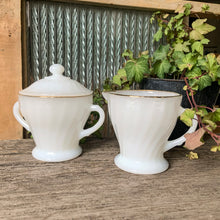 Load image into Gallery viewer, Set of vintage Fire-King "Swirl Golden Shell Lustre" milk glass creamer and covered super bowl, featuring a swirled pressed glass with gold rims. Crafted by Anchor Hocking, USA, circa 1970s. Simple and elegant, these pieces will complement any tablescape! In excellent condition, free from chips/wear. Creamer measures 3 3/8 x 3 1/2 inches Covered sugar measures 3 3/4 x 4 1/2 inches