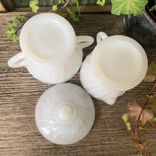 Load image into Gallery viewer, Set of vintage Fire-King "Swirl Golden Shell Lustre" milk glass creamer and covered super bowl, featuring a swirled pressed glass with gold rims. Crafted by Anchor Hocking, USA, circa 1970s. Simple and elegant, these pieces will complement any tablescape! In excellent condition, free from chips/wear. Creamer measures 3 3/8 x 3 1/2 inches Covered sugar measures 3 3/4 x 4 1/2 inches