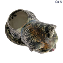 Load image into Gallery viewer, Vintage skillfully hand painted figural tabby cat ceramic planters with intense expressions. These planters have a distinct painting style and date to the 1930s. Features a dark charcoal tabby cat with soulful gray eyes and gray ears, wearing a blue bow tie. In excellent condition, free from chips/cracks/repairs. Impressed mark on the bottom reads, Made in Japan. Measure 6 1/8 x 4 1/2 x 7 inches