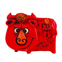 Load image into Gallery viewer, Adorable vintage zodiac sign ceramic coin bank of a grinning bull representing the astrological sign of Taurus. The bull is painted red with embossed features including the word "Taurus," tuft of fur and a flower with the dates April 20-May 20. Crafted by Noritake, Japan, circa 1970s and imported by Giftcraft Canada. A great retro collectible for the Taurus in your life!