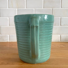 Load image into Gallery viewer, Vintage teal glazed horizontal ribbed stoneware pitcher. Crafted by Monmouth Western Stoneware, USA, 1920s. Add this solid utilitarian piece to your farmhouse decor or art pottery collection!
In excellent condition, no chips/cracks/repairs, age-related crazing. Maker's mark.
Measures 7 3/8 x 4 1/2 x 5 inches (incl. spout and handle)