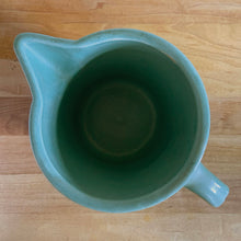 Load image into Gallery viewer, Vintage teal glazed horizontal ribbed stoneware pitcher. Crafted by Monmouth Western Stoneware, USA, 1920s. Add this solid utilitarian piece to your farmhouse decor or art pottery collection!
In excellent condition, no chips/cracks/repairs, age-related crazing. Maker's mark.
Measures 7 3/8 x 4 1/2 x 5 inches (incl. spout and handle)