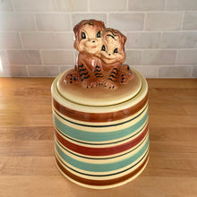 Load image into Gallery viewer, Adorable vintage hand painted ceramic cookie jar topped with a pair of anthropomorphic tiger cubs on a barrel with horizontal stripes in brown, black, turquoise and cranberry on a beige ground. Robinson Ransbottom Pottery Co., 1950s. A excellent example of mid-century era kitsch. Add this darling cookie jar to your kitchen decor or cookie jar collection!
In overall great condition with worn chips on the ears and age-related crazing. Marked R.R.P. Co. Roseville Ohio No - 386.
Measures 7 1/4 x 10 inches