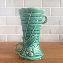 Load image into Gallery viewer, Vintage Art Deco gloss turquoise ring handled trumpet vase with leaves and berries on a ringed body. Crafted by McCoy Pottery, 1940s. This rare piece is must for any McCoy art pottery collector!
In as found vintage condition, no chips/repairs, tight hairline crack and crazing commensurate with age. Unmarked.
Measures 3 1/4 x 5 3/4 inches