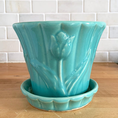 A vintage aqua art pottery jardiniere or planter pot, glazed in glossy turquoise featuring three dimensional tulips on a vertically ribbed background with attached underplate. Crafted by Shawnee Pottery, USA, circa 1940s. An excellent addition to any art pottery collection!  In excellent condition, free from chips and cracks. Marked 