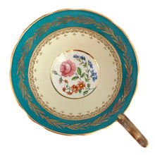 Load image into Gallery viewer, This highly sought after vintage Bone China teacup and saucer with scalloped rim features a hand painted turquoise and pale yellow banded interior on a white ground, lavishly decorated with gold gilt filigree, complemented by colourful floral bouquets in the bottom of the cup and centre of the saucer. Crafted by Aynsley, England. Backstamp indicates production between 1934 - 1950s. A stunning addition to your teacup collection!