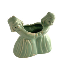 Load image into Gallery viewer, Sweet vintage ceramic planter featuring two dancing Dutch girls, finished in pale green glaze. Crafted by McCoy Pottery, USA, circa 1930s. Perfect to use a decor piece, a tiny houseplant or repurpose to hold make-up brushes. Makes an excellent gift! In excellent condition, free from chips/cracks. Measures 4 3/4 x 2 3/8 x 4 1/2 inches