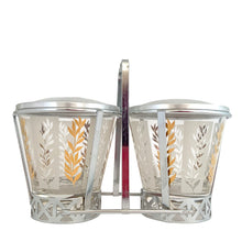 Load image into Gallery viewer, Vintage 2-part glass condiment server featuring alternating 22kt gold leaves and clear leaves on a white stripe and pinecone embossed aluminum lids in chrome caddy. Crafted by Dominion Glass, Canada, 1950s. Love the conical shape of the glass and the styling on the caddy....very mid-century modern and a great way to serve your favourite fixings.
In excellent condition, no chips.
Overall measures 7 3/4 x 4 x 5 1/2 inches