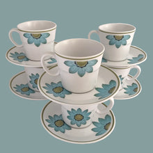 Load image into Gallery viewer, Vintage Progression Up-Sa Daisy high quality stoneware teacup and saucer features an aque blue daisy with moss green and black centres and moss green band at the rim. Crafted by Noritake, Japan, 1966 - 1979. This darling flower pot shaped teacup and saucer will add tons of vintage charm to your table! In excellent condition and appear unused. Free from chips/cracks/repairs. Colours are vibrant. Teacup measures 3 3/8 x 3 inches Saucer measures 6 inches Capacity 8 ounces