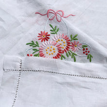 Load image into Gallery viewer, This beautiful white linen bridge-sized square tablecloth features a pale blue wedding back filled with pink , yellow and green florals topped off with a pretty pink bow. This dreamy linen will look amazing on any table. Use your imagination to repurpose into pillows or wearables. In excellent condition, free from tears or stains. Circa 1950s. Measures 40 x 41 inches