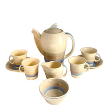 Load image into Gallery viewer, Vintage Art Deco style Wedding Ring coffee set in the blue, rust and gray colourway. Crafted by Susie Cooper, England, 1930s. This kestrel-shaped set comprised of a coffee pot with lid, creamer and sugar with four demitasse cups and saucers.
The set is in generally good vintage condition with no chips, cracks, or repairs. Each piece shows age-related crazing. The coffee pot has a chip at the top of the spout, and the sugar bowl has staining on the bottom. All pieces have maker's marks.