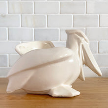 Load image into Gallery viewer, Vintage mid-century era matte white Pelican pattern planter. Crafted by Nelson McCoy Pottery, 1948. Perfect as a succulent planter or to hold baby accessories as part of your nursery decor! This rare piece is must for any art pottery collector.
In excellent vintage condition, no chips/cracks/repairs, age-related crazing and interior staining. Manufacturer's glaze pops. Maker's mark.
Measures 7 3/4 x 4 1/4 x 5 1/2 inches