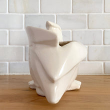 Load image into Gallery viewer, Vintage mid-century era matte white Pelican pattern planter. Crafted by Nelson McCoy Pottery, 1948. Perfect as a succulent planter or to hold baby accessories as part of your nursery decor! This rare piece is must for any art pottery collector.
In excellent vintage condition, no chips/cracks/repairs, age-related crazing and interior staining. Manufacturer's glaze pops. Maker's mark.
Measures 7 3/4 x 4 1/4 x 5 1/2 inches
