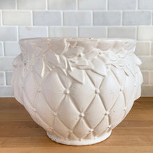 Load image into Gallery viewer, Vintage matte white Tierra Cushion jardiniere planter pot, features an overlapping floral leaf pattern around the top rim, a diamond quilted body and ribbon handles. Crafted by McCoy Pottery, USA, 1950s. A must-have for any McCoy collector or container gardener!
In excellent vintage condition, no chips/cracks/repairs, age-related crazing, manufacturer's glaze pops. Maker's mark.
Measures 9 x 7 3/8 inches