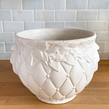 Load image into Gallery viewer, Vintage matte white Tierra Cushion jardiniere planter pot, features an overlapping floral leaf pattern around the top rim, a diamond quilted body and ribbon handles. Crafted by McCoy Pottery, USA, 1950s. A must-have for any McCoy collector or container gardener!
In excellent vintage condition, no chips/cracks/repairs, age-related crazing, manufacturer's glaze pops. Maker's mark.
Measures 9 x 7 3/8 inches