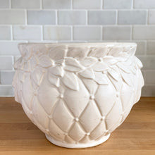 Load image into Gallery viewer, Vintage matte white Tierra Cushion jardiniere planter pot, features an overlapping floral leaf pattern around the top rim, a diamond quilted body and ribbon handles. Crafted by McCoy Pottery, USA, 1950s. A must-have for any McCoy collector or container gardener!
In excellent vintage condition, no chips/cracks/repairs, age-related crazing, manufacturer's glaze pops. Maker's mark.
Measures 9 x 7 3/8 inches