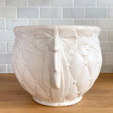 Load image into Gallery viewer, Vintage matte white Tierra Cushion jardiniere planter pot, features an overlapping floral leaf pattern around the top rim, a diamond quilted body and ribbon handles. Crafted by McCoy Pottery, USA, 1950s. A must-have for any McCoy collector or container gardener!
In excellent vintage condition, no chips/cracks/repairs, age-related crazing, manufacturer's glaze pops. Maker's mark.
Measures 9 x 7 3/8 inches