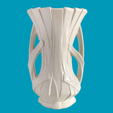 Load image into Gallery viewer, Vintage shiny white glazed ribbon strap vase with double handles. Crafted by McCoy Pottery, 1940s. A must for any art pottery collector!
In excellent condition, no chips, no cracks, no repairs and no visible crazing which is incredible for a piece of this age. Maker's mark on the bottom.
Measures 7 3/4 x 12 inches