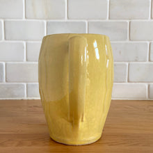 Load image into Gallery viewer, Charming vintage sunny yellow milk pitcher featuring embossed vertical scalloped pattern. Crafted by McCoy Pottery, 1964. This collectible pitcher is the perfect vessels to hold a charming bouquet of spring flowers or a lovely gift for an art pottery collector.
In vintage condition, no chips/cracks/repairs, age-related crazing and staining, manufacturer's glaze pops. Maker's mark.
Measures 6 x 3 1/2 x 5 1/8 inches
