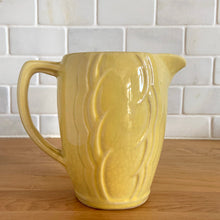 Load image into Gallery viewer, Charming vintage sunny yellow milk pitcher featuring embossed vertical scalloped pattern. Crafted by McCoy Pottery, 1964. This collectible pitcher is the perfect vessels to hold a charming bouquet of spring flowers or a lovely gift for an art pottery collector.
In vintage condition, no chips/cracks/repairs, age-related crazing and staining, manufacturer's glaze pops. Maker's mark.
Measures 6 x 3 1/2 x 5 1/8 inches